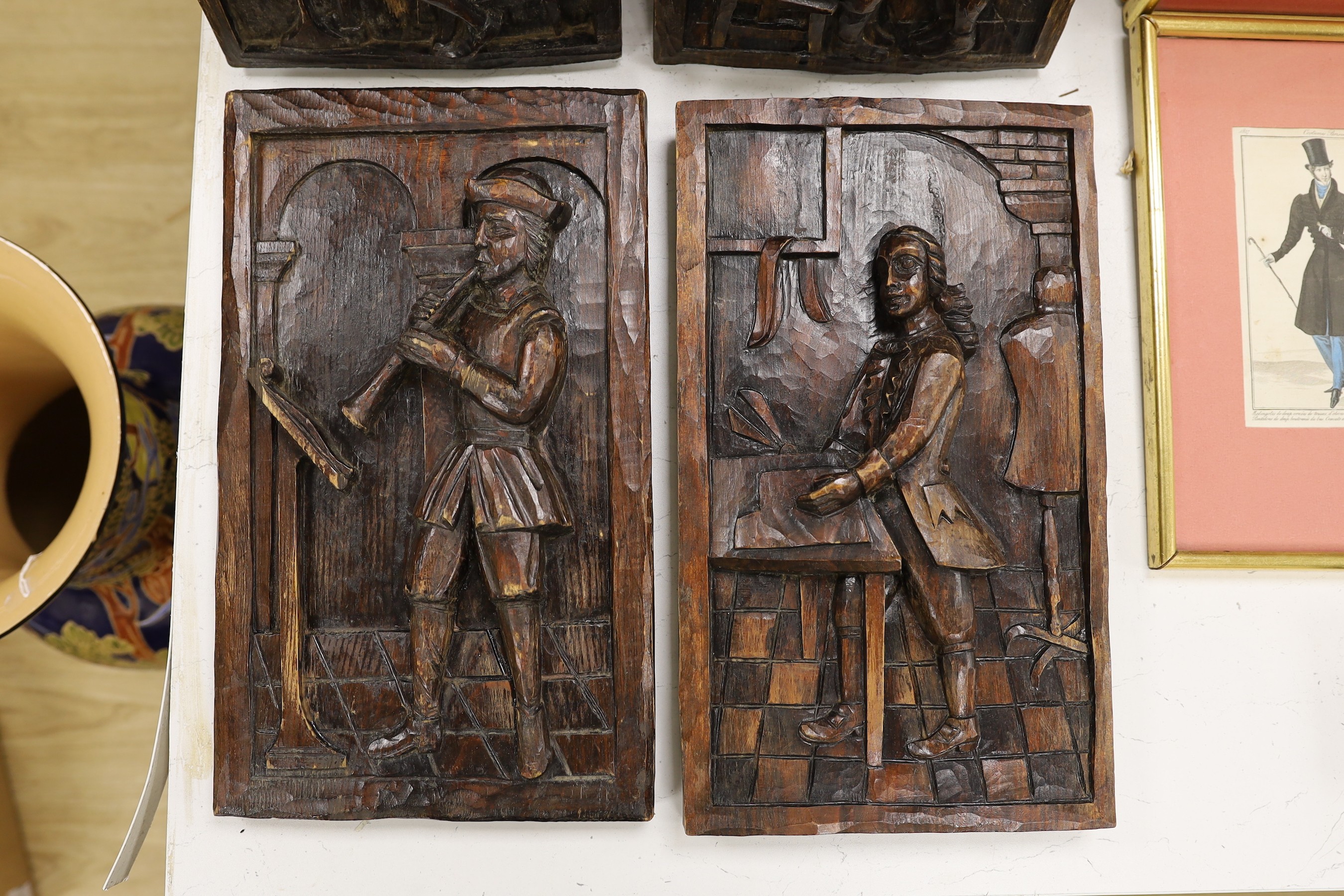 A set of four carved and stained pine figurative panels, 39cms high x 23cms wide